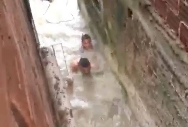 Pessoas tentam fugir de alagamento nadando no Recife (PE)